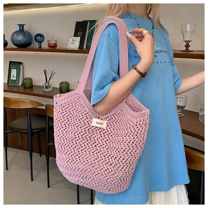 Détail du sac cabas en crochet rose avec texture tissée et étiquette de logo blanche