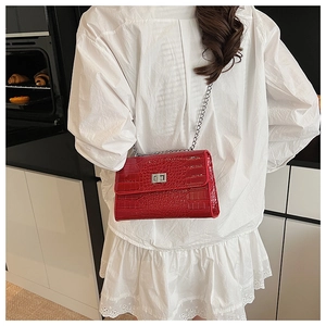 Close-up of red crocodile embossed shoulder bag featuring a silver metal twist lock