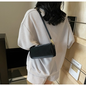 Close-up of black lychee texture leather mini pillow bag with golden metal hardware