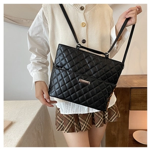 Detail of black quilted leather tote bag showing metallic logo and elegant stitching