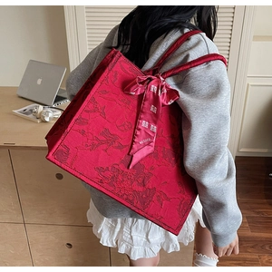 Macro shot of red jacquard wedding tote bag with silk ribbon featuring a classic logo