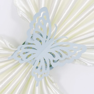 Detail of laser-cut light blue butterfly napkin ring with intricate pattern on white satin