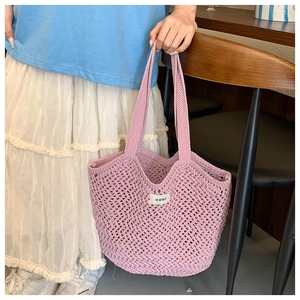 Détails du tissage du sac cabas en crochet rose avec étiquette minimaliste blanche