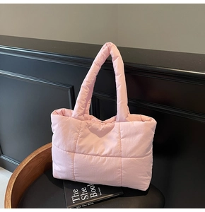 Détail d'un sac cabas rembourré matelassé rose posé sur une chaise en bois foncé