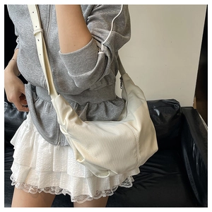 Close-up of ivory corduroy crescent bag showing vertical texture and adjustable strap