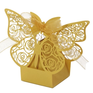 Macro detail of laser-cut rose patterns on a gold butterfly candy gift box with silk ribbon