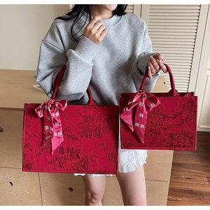 Comparison of large and small red brocade tote bags with elegant floral jacquard texture