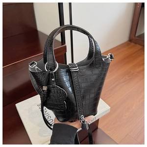 Macro detail of classic black crocodile pattern mini bucket bag with silver lock and pendant
