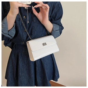 Detailed shot of white faux crocodile leather texture and silver chain strap on crossbody bag