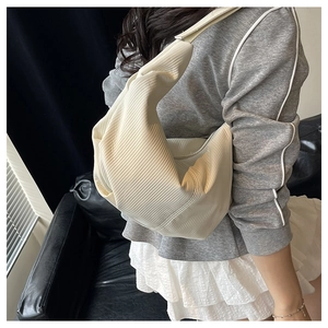 Detail view of the white pleated dumpling bag with elegant accordion folds and wide strap