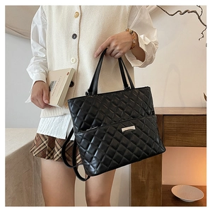 Detail of black quilted leather tote bag featuring classic diamond stitching and silver hardware
