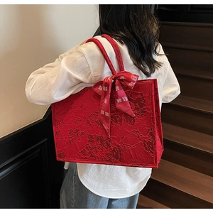 Detail of red wedding tote bag featuring floral jacquard texture and silk bow ribbon