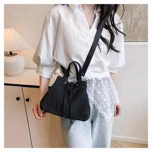 Detail of black nylon drawstring bucket bag showing wide fabric shoulder strap and texture