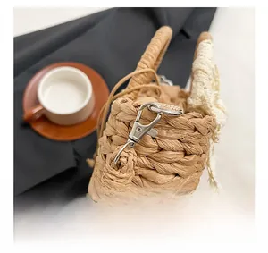 Détail du crochet métallique et du bord en dentelle du sac de plage en paille tressée