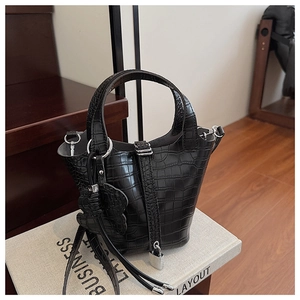 Close-up of black crocodile pattern bucket bag with silver lock and bear charm accessory