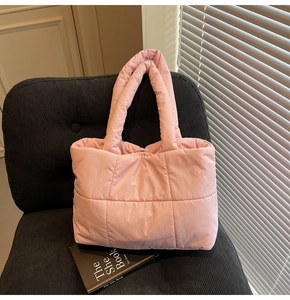 Gros plan d'un sac cabas matelassé rose avec poignées rembourrées sur chaise velours
