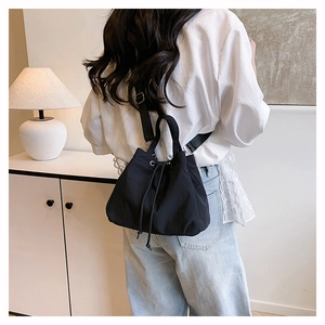 Detail of a black nylon drawstring bucket bag showing its textured fabric and adjustable strap