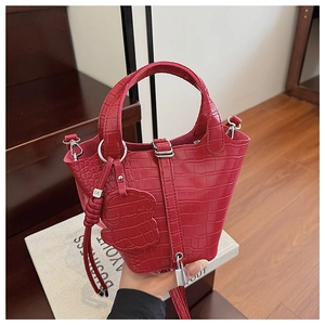 Detail of red croc-embossed bucket bag with metallic lock and cute dog leather charm