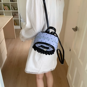 Détail d'un mini sac à dos rayé bleu avec des froufrous noirs et un nœud élégant