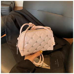Detail of pink shell bag with diamond quilt stitching and metallic rivet accents