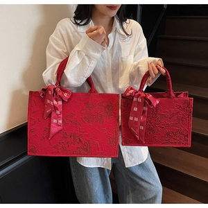 Detailed macro view of red jacquard fabric tote bags with festive floral wedding patterns