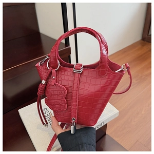 Macro detail of red crocodile texture mini handbag with silver buckle and puppy charm