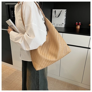 Detail of tan woven leather large tote bag shown on model in a minimalist setting