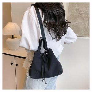 Detail of minimalist black nylon drawstring bucket bag with adjustable wide shoulder strap