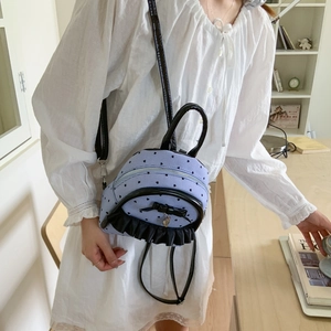 Détail d'un mini sac à dos rayé avec motifs cœurs et nœud noir sur un modèle