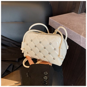Detail of white quilted shell bag with sparkling crystal embellishments and tied strap