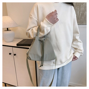 Detail of sage green nylon drawstring bucket bag showing adjustable strap and texture