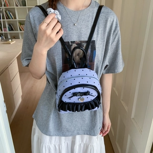 Détail du mini sac à dos rayé bleu clair avec nœud noir et pendentif cœur sur modèle