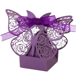 Macro view of purple butterfly wedding favor box with laser-cut rose patterns and ribbon