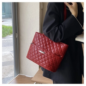 Detailed view of the red quilted shoulder bag with elegant silver logo plaque