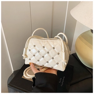 Detail shot of white quilted crossbody bag featuring diamond stitching and metal studs