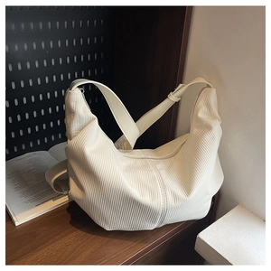 Detail of minimalist cream hobo bag with pleated texture and adjustable buckle strap