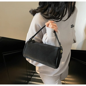 Detail view of black lychee grain leather pillow bag with elegant golden metal buckle