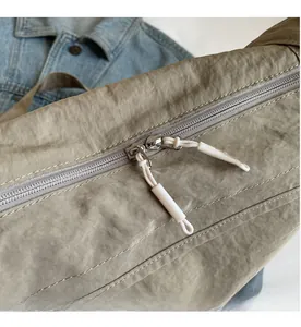Macro shot of smooth metal zipper with cord puller on khaki pleated crossbody bag