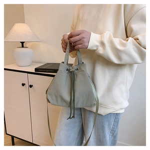 Detail of sage green nylon drawstring bucket bag with handle and metal eyelets