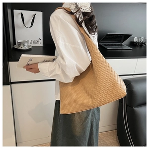 Detail shot of camel woven hobo shoulder bag shown on model in modern office setting