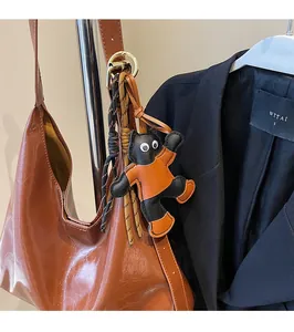 Close-up of a quirky black cat charm in orange outfit on a brown leather tote bag