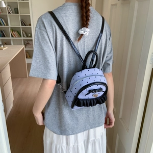 Détail du sac à dos rayé bleu clair avec des volants noirs et un motif de cœurs