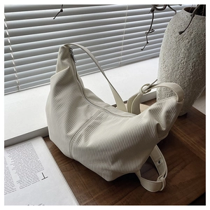 Detail of minimalist cream pleated crescent bag with adjustable wide shoulder strap