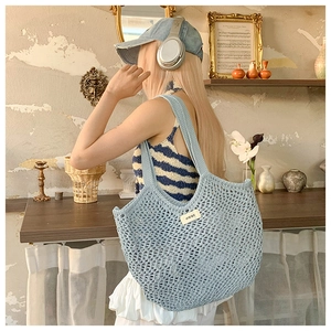 Détail d'un sac cabas au crochet bleu clair avec texture tissée et petite étiquette de logo