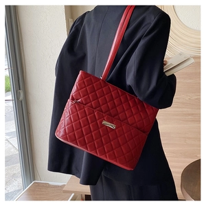 Rear view of a model wearing the red quilted tote bag over a black blazer for a chic look