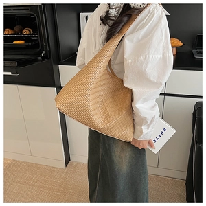 Detailed view of camel woven leather hobo bag worn by model in a modern setting