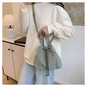 Detail of green drawstring nylon bucket bag showing textured fabric and casual crossbody style