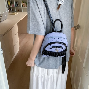 Gros plan du mini sac à dos à rayures bleues avec cœurs noirs, nœud et pendentif cœur