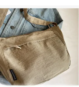 Detail of khaki nylon crossbody bag with side letter tag and wide shoulder strap
