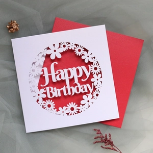 Detail showing a laser-cut Happy Birthday card with a red envelope on a mesh fabric background